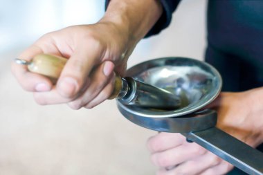 Pirinç tamircisi küf üzerindeki trompetin çanı darbelerini kaldırıyor.