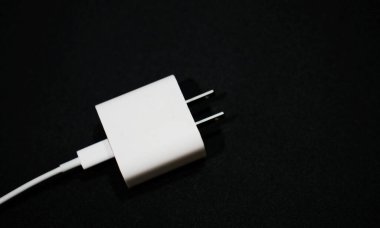 Siyah arkaplanı olan beyaz telefon şarj cihazı.