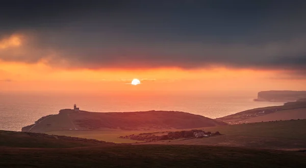 英国东南萨塞克斯海岸东南方海滩头悬崖边的贝尔托特灯塔后面的戏剧性的天空和日落 — 图库照片