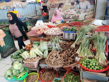 Magelang, Central Java - Endonezya, 27 Aralık 2023 Küçük bir iş kadını çeşitli sebzeler, meyveler, otlar ve diğer yiyecekleri geleneksel bir pazarda satıyor..