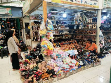 Magelang, Central Java - Endonezya, 27 Aralık 2023 Küçük bir iş yürüten bir adam ayakkabı ve ayakkabı satışı ve diğer ihtiyaçlar geleneksel bir pazar yerinde.