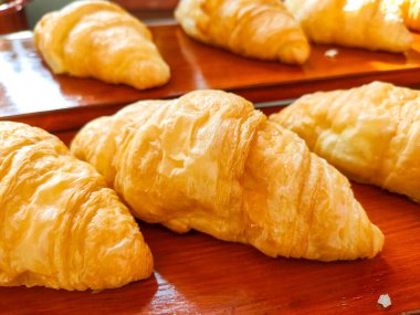 Kruvasan keki lezzetli, taze ve gevrek görünüyor. Sabah yemeğinin bir parçası olarak. Tahta tepside servis edilir..