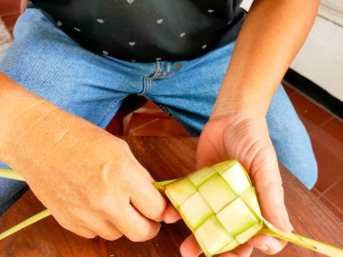Bir adam ketuplu Janur kuning yapıyor, küp şeklinde bir Endonezya bayramı yemeği pirinçle dolu..