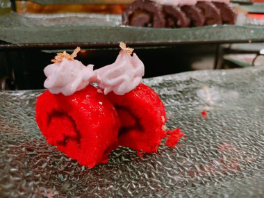 İlginç malzemelerle dolu cam bir tabakta servis edilen kırmızı kadife kek rulosu çok iştah açıcıdır..