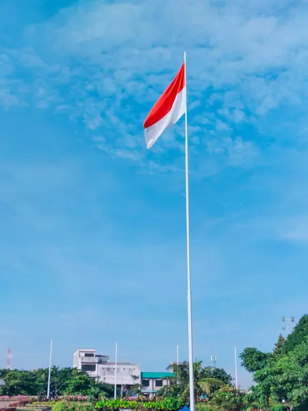 stock image Surabaya - Indonesia, April 18, 2023.The Indonesian Red and White flag flies at the Tugu Pahlawan field in Surabaya. Trees in the background.