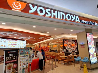 Surabaya - Indonesia, October 9, 2024.Front view of Restaurant Yoshinoya with Japanese atmosphere, light and attractive wooden elements. Eye level view. clipart