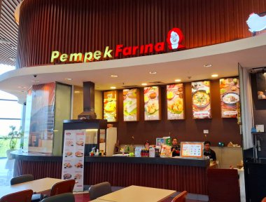 Surabaya - Indonesia, October 8, 2024.The front view of the Pempek Farina booth provides Palembang Indonesian specialties. Modern wooden design, looks elegant, inside a mall in Surabaya. Eye view level. clipart