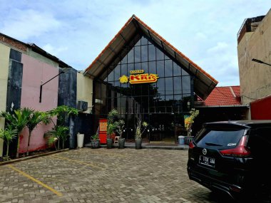 Surabaya, Endonezya - 11 Aralık 2024Front View of Warung Makan Bu Kris, geleneksel modern tarz. Güçlü ahşap, metal ve cam elementlerle, koyu renklerle.