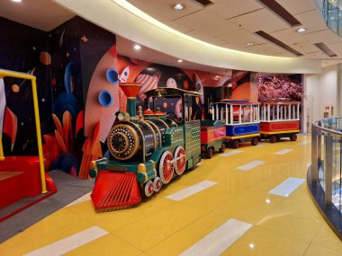 Surabaya - Endonezya, 25 Şubat 2025. Çocukların eğlencesi için oyuncak bir tren. Alışveriş merkezinde birkaç yolcu vagonu çekerek..