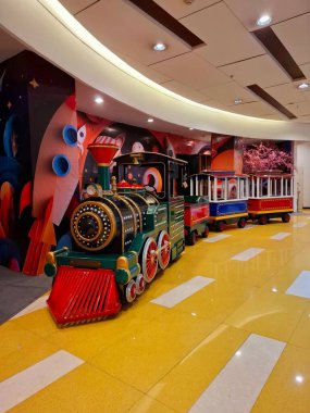 Surabaya - Endonezya, 25 Şubat 2025. Çocukların eğlencesi için oyuncak bir tren. Alışveriş merkezinde birkaç yolcu vagonu çekerek..