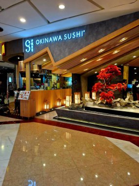 Jakarta - Endonezya, 11 Mart 2025. Bir alışveriş merkezindeki OKINAWA SUSHI Japon restoranının ön görüntüsü. Japon nüanslarını davet eden dinamik bir tasarıma sahip, sıcak, modern, zarif, lüks. Göz düzeyi görünümü.