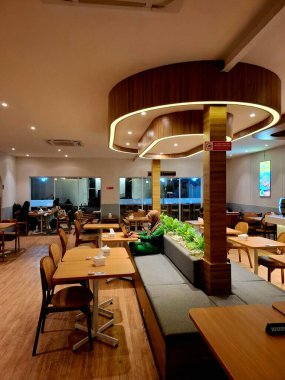 Surabaya, Endonezya, 21 Temmuz 2025. Elektrik prizli öğrenci dostu bir kafe ve rahat çalışma için Wi-Fi. Çekici retro iç tasarım ve rahat masa ve sandalyeler.