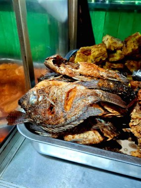 Geleneksel bir Cava yemeği olan kızarmış mujahir balığı, geleneksel bir Cava lokantasında basit bir vitrinde satılıyor. Yakın plan fotoğraf..