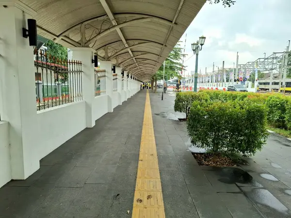 Yogyakarta, Endonezya, 4 Temmuz 2025. Tren istasyonuna giden düz bir yaya yolu. Öncü çizgi, göz düzeyi görünümü.