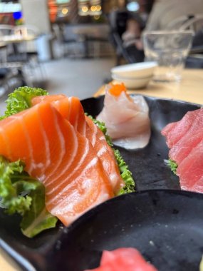 Lokantada siyah tabakta somon ve ton balığı.