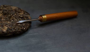 Bastırılmış Sheng Puerh ve siyah arka planda bir Puerh bıçağı.