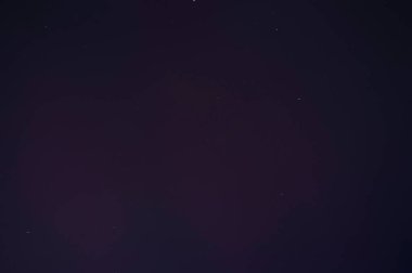 Gece gökyüzü yıldızlarla ve mor kuzey ışıklarıyla