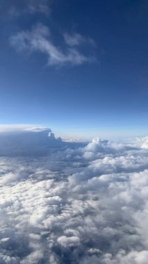 Mavi gökyüzü arkaplanındaki bulutların üzerine bak. Uçak penceresinden görüntüle.
