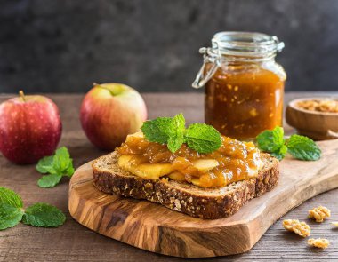 Chunky Apple Preserve ve yontulmuş tahta üzerinde taze nane şekerli çok tahıllı tost.