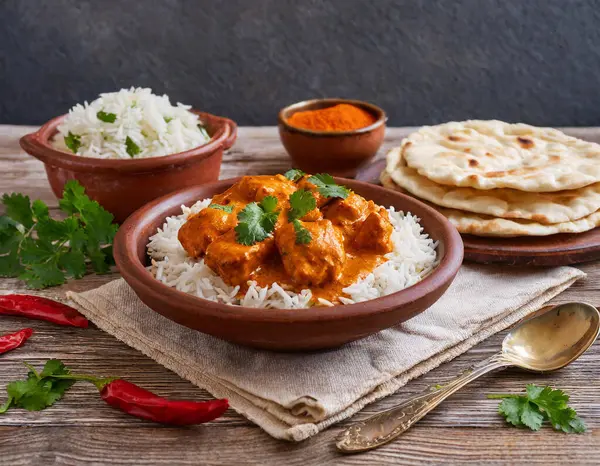 Tavuk tikka masala baharatlı körili et tabakta pilav ve naan ekmeği.