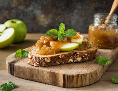 Chunky Apple Preserve ve yontulmuş tahta üzerinde taze nane şekerli çok tahıllı tost.