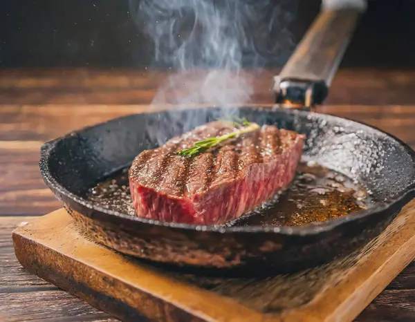 Ahşap bir masada sıcak tavada pişen Wagyu bifteğinin yakın çekim görüntüsü..