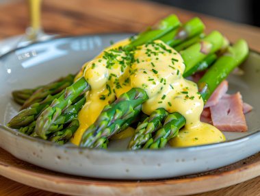 Bir tabakta Hollandaise soslu ve jambonlu kuşkonmaz.