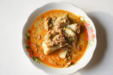 Lontong sayur ya da sebzeli pirinç keki, beyaz bir tabakta beyaz arka planda bulunan tipik bir Endonezya yemeğidir.