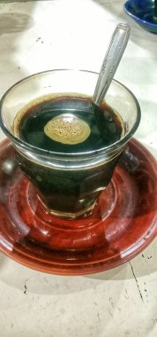 Küçük bir tabakta bir bardak sıcak kahve.