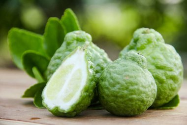 Bergamot meyveleri ya da ahşap masada dilimlenmiş kaffir limonu ve doğal yeşil arka plan