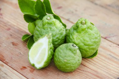 Geleneksel ahşap masada izole edilmiş taze bergamot ya da dilimlenmiş kaffir limon meyvesi.