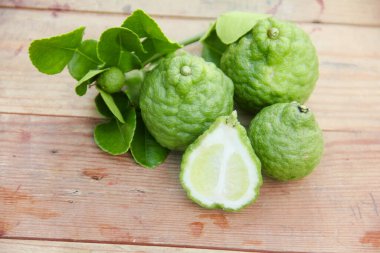Geleneksel ahşap masada izole edilmiş taze bergamot ya da dilimlenmiş kaffir limon meyvesi.