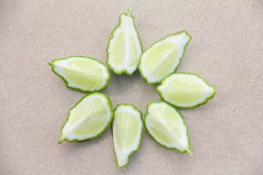 Geleneksel ahşap masada izole edilmiş taze bergamot ya da dilimlenmiş kaffir limon meyvesi.