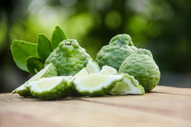 Bergamot meyveleri ya da ahşap masada dilimlenmiş kaffir limonu ve doğal yeşil arka plan