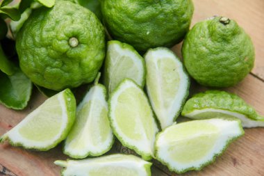 Geleneksel ahşap masada izole edilmiş taze bergamot ya da dilimlenmiş kaffir limon meyvesi.