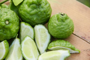 Geleneksel ahşap masada izole edilmiş taze bergamot ya da dilimlenmiş kaffir limon meyvesi.