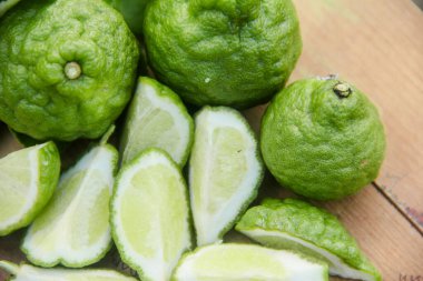 Geleneksel ahşap masada izole edilmiş taze bergamot ya da dilimlenmiş kaffir limon meyvesi.