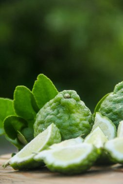 Bergamot meyveleri ya da ahşap masada dilimlenmiş kaffir limonu ve doğal yeşil arka plan