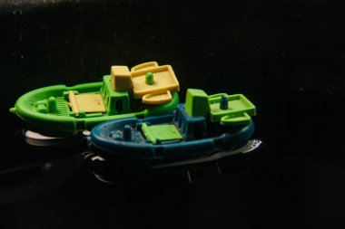 Plastikten yapılmış minyatür balıkçı teknesi ve karanlık sularda yelken açmak.