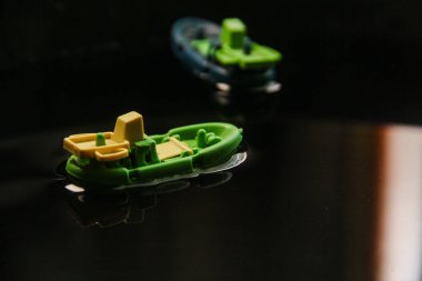 Plastikten yapılmış minyatür balıkçı teknesi ve karanlık sularda yelken açmak.