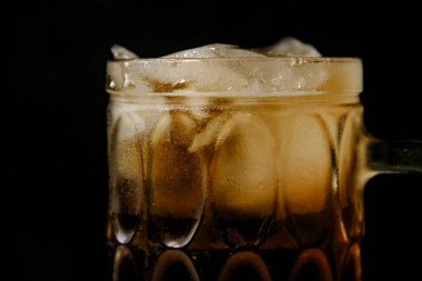 Soğuk çay içmek, siyah arka planda buzlu çay içmek.