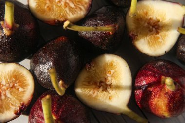 Taze ve doğranmış incirler beyaz ahşap bir masada, yiyecek arka planında.