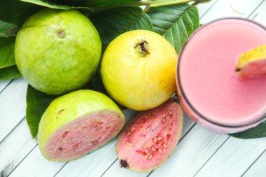 Guava suyu, cam bardakta taze guava suyu ve dokulu ahşap bir arka planda dilimlenmiş guava.