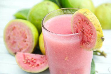 Guava suyu, cam bardakta taze guava suyu ve beyaz arka planda dilimlenmiş guava.