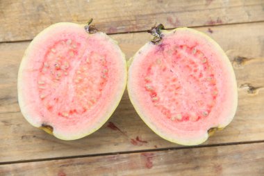 Taze taze guava ve dilimlenmiş guava, ahşap doku arka planında dilimlenmiş guava