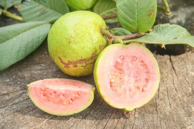 Taze taze guava ve dilimlenmiş guava, ahşap doku arka planında dilimlenmiş guava