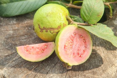 Taze taze guava ve dilimlenmiş guava, ahşap doku arka planında dilimlenmiş guava