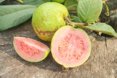 Taze taze guava ve dilimlenmiş guava, ahşap doku arka planında dilimlenmiş guava