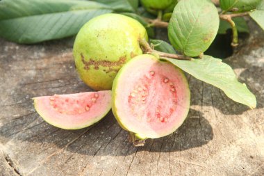 Taze taze guava ve dilimlenmiş guava, ahşap doku arka planında dilimlenmiş guava
