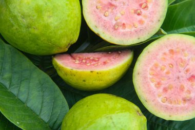 Taze guava ve dilimlenmiş guava yeşil guava yaprakları üzerinde.